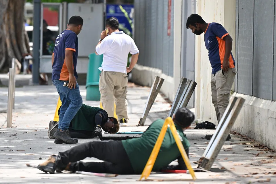 Dua pekerja kontraktor Nparks (ves hijau) kelihatan memeriksa beberapa lubang longkang di pejalan kali Lorong 1, Toa Payoh