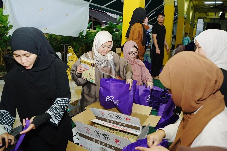 Menteri Negara (Kesihatan merangkap Penerangan dan Pembangunan Digital), Cik Rahayu Mahzam (dua dari kiri); dan Penasihat Pertubuhan Akar Umbi (GRO) GRC East Coast, Cik Hazlina Abdul Halim (tiga dari kiri), menyertai sekitar 100 belia di Masjid Kassim pada awal pagi 7 Mac untuk membungkus pek keperluan dapur bagi keluarga rentan.