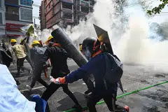 MASIH BERGOLAK: Para penunjuk perasaan di Yangon lari apabila gas pemedih mata dilemparkan bagi memaksa mereka bersurai dalam bantahan semalam. - Foto AFP