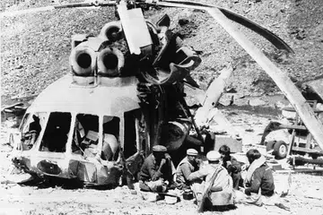 PERTAHAN NEGARA: Mujahidin Afghanistan makan tengah hari di sisi sebuah helikopter Soviet Union yang ditembak jatuh dalam satu serangan pejuang itu di Nuristan. Soviet Union melanggar Afghanistan pada 1979 tetapi menghadapi tentangan kuat dan berundur pada 15 Februari 1989. - Foto fail REUTERS