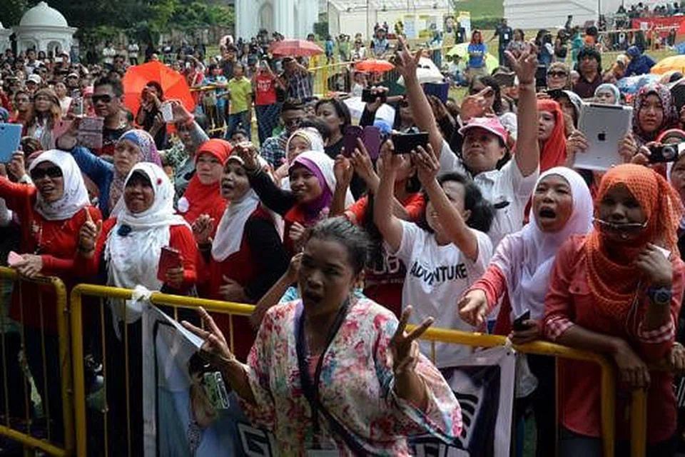 BERSORAK KEGEMBIRAAN: Penonton, yang rata-rata warga Indonesia yang bekerja di sini, giat mengambil gambar idola mereka yang sedang beraksi di atas pentas.