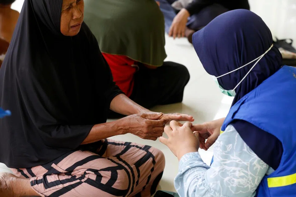 Sukarelawan kesihatan membantu penduduk dengan memberikan pemeriksaan kesihatan percuma di kawasan terjejas banjir di Kampung Babo, Aceh Tamiang, Aceh, Indonesia pada 6 Februari 2026. Pemerintah Indonesia menyatakan proses pemulihan pascabencana masih perlahan berikutan beberapa halangan seperti kerosakan infrastruktur jambatan dan kesukaran menentukan lokasi penempatan semula mangsa banjir.