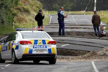 KESAN GEMPA: Pegawai polis dan penduduk setempat memeriksa jalan raya yang merekah dekat bandar Ward, New Zealand, semalam. - Foto REUTERS