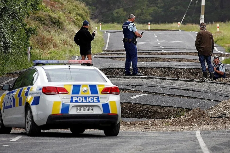KESAN GEMPA: Pegawai polis dan penduduk setempat memeriksa jalan raya yang merekah dekat bandar Ward, New Zealand, semalam. - Foto REUTERS