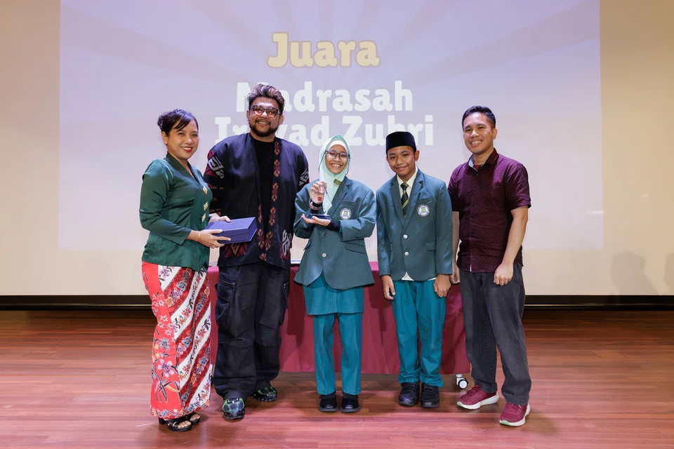 MENANG PERTANDINGAN: Pengasas kumpulan penulis, Meja Conteng,  Encik Hidayat Nordin (dua dari kiri), bersama Heidi Qaysara Muhamad Helmi (tengah) dan Mohamed Adam Luqman Mohamed Fadhilad (dua dari kanan) dari Madrasah Irsyad Zuhri Al-Islamiah, muncul juara Penterjemah Pintar 2026. Bersama mereka ialah anggota juri, Cik Siti Nurbayah Ismail (kiri) dan Encik Zulhafiz Zainal.