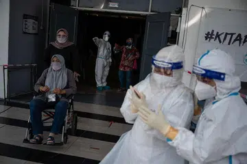 BERSIAP BUAT UJIAN: Kakitangan perubatan mengenakan pakaian khas untuk melakukan ujian di pusat ujian Covid-19 di Shah Alam, Kuala Lumpur, beberapa hari lalu. - Foto AFP