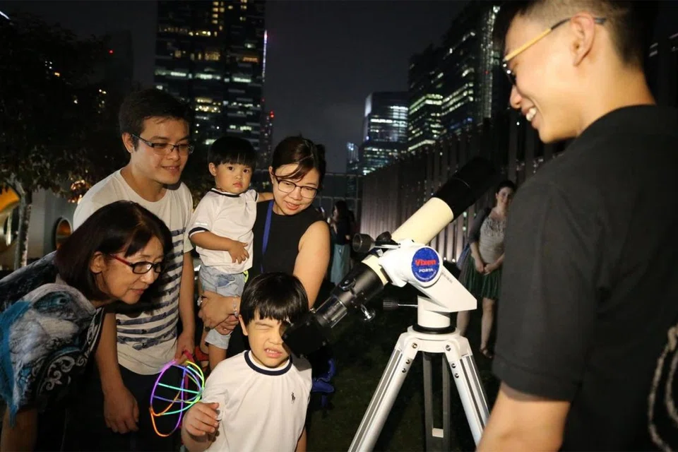TEROPONG ANGKASA: Pengunjung berpeluang melihat bulan menggunakan teleskop yang disediakan oleh Pusat Sains Singapura bagi acara acara ‘Mid-Autumn Family Fun’ anjuran Pusat Kebudayaan Cina Singapura (SCCC).