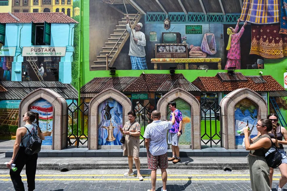 Mural oleh Yip Yew Chong di latar belakang menggambarkan suasana Kampong Gelam pada zaman dahulu. Di sebelahnya, lukisan dinding bertema budaya Oman seperti kapal layar dan pokok kurma memperlihatkan sejarah perdagangan di kawasan Muscat Street.