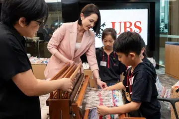 Ketua Bersama UBS Global Wealth Management, Asia Pasifik yang juga Ketua Negara UBS Singapore, Cik Young Jin Yee (dua dari kiri), dan beberapa kanak-kanak daripada badan amal, Care Corner, menyumbang pada hasil tenunan dewangga yang kelak mencecah sepanjang 60 meter, sempena pelancaran program seni masyarakat syarikat ini, ‘Art for All’ (Seni untuk Semua).