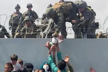 SERAHKAN BAYI: Keluarga seorang bayi Afghanistan diserahkan kepada anggota tentera Amerika di tembok di lapangan terbang di Kabul agar dapat dibawa keluar dari Afghanistan. - Foto REUTERS