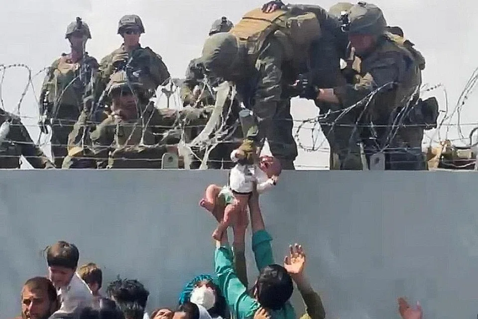 SERAHKAN BAYI: Keluarga seorang bayi Afghanistan diserahkan kepada anggota tentera Amerika di tembok di lapangan terbang di Kabul agar dapat dibawa keluar dari Afghanistan. - Foto REUTERS