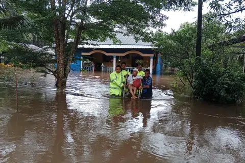 Para pegawai daripada Balai Polis Kuala Sedili membantu seorang mangsa banjir dengan memindahkannya dari kediaman yang terjejas ke lokasi yang lebih selamat.