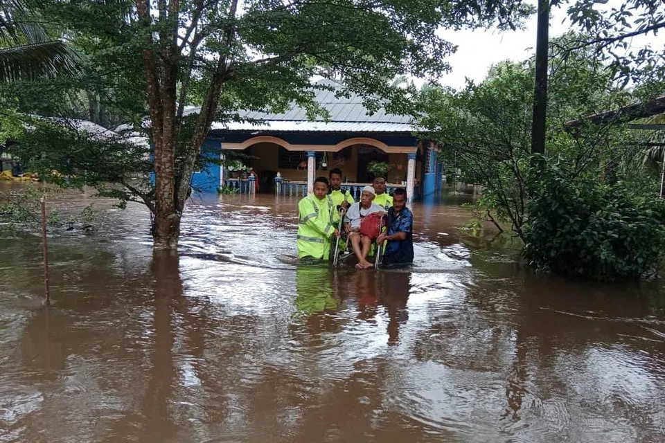 Para pegawai daripada Balai Polis Kuala Sedili membantu seorang mangsa banjir dengan memindahkannya dari kediaman yang terjejas ke lokasi yang lebih selamat.
