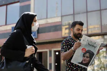 DIKECAM HEBAT: Foto fail menunjukkan seorang lelaki membaca akhbar yang memaparkan Cik Mahsa Amini, seorang wanita yang meninggal dunia selepas ditahan polis Iran setahun lalu. 