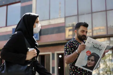 DIKECAM HEBAT: Foto fail menunjukkan seorang lelaki membaca akhbar yang memaparkan Cik Mahsa Amini, seorang wanita yang meninggal dunia selepas ditahan polis Iran setahun lalu. 