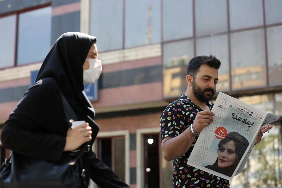 DIKECAM HEBAT: Foto fail menunjukkan seorang lelaki membaca akhbar yang memaparkan Cik Mahsa Amini, seorang wanita yang meninggal dunia selepas ditahan polis Iran setahun lalu. 