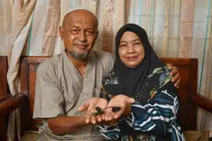 ALAT BANTUAN: Cik Roslinah Rawi dan suami, Encik Mohamad Jantan B Mis tunjukkan implan cochlear yang dipasang ke telinganya untuk membantu beliau mendengar dengan lebih jelas. - Foto BH oleh CHONG JUN LIANG