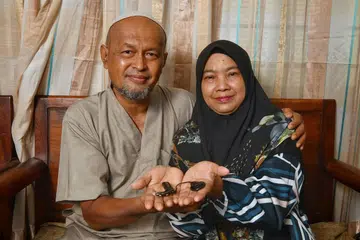 ALAT BANTUAN: Cik Roslinah Rawi dan suami, Encik Mohamad Jantan B Mis tunjukkan implan cochlear yang dipasang ke telinganya untuk membantu beliau mendengar dengan lebih jelas. - Foto BH oleh CHONG JUN LIANG