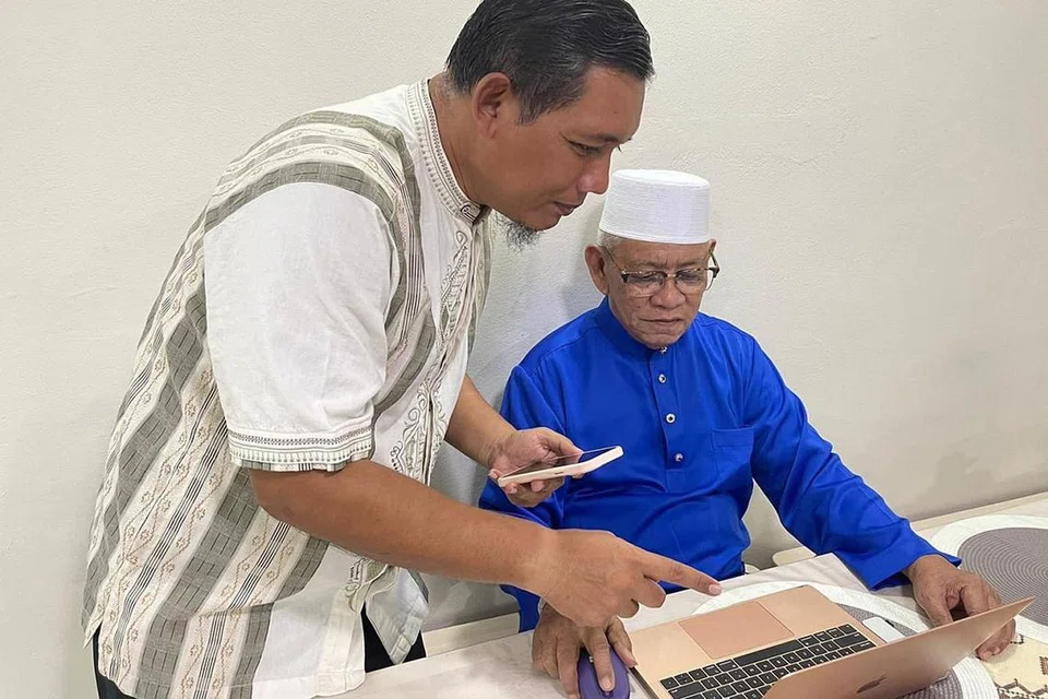 BANTU BAPA MENTUA MANFAATKAN TEKNOLOGI: Sukarelawan Masjid Al-Islah, Encik Mohamed Faizul Othman, sentiasa bersedia membantu bapa mentuanya, Haji Sujaair Ali, agar beliau berupaya mengikuti pengajian agama dalam dalam talian. - Foto MASJID AL-ISLAH