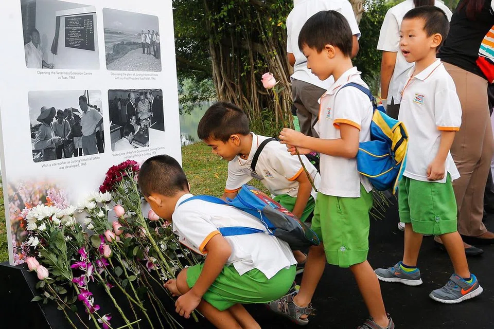 ACARA DI SERATA PULAU - SI KECIL JUGA KENANG JASA: Kanak-kanak ini meletakkan bunga di depan gambar mendiang Encik Lee Kuan Yew di Taman Tasik Jurong semalam. - Foto THE STRAITS TIMES 