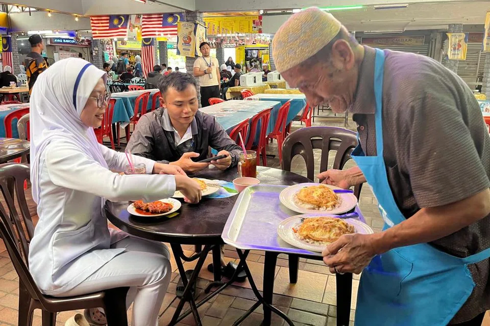 Walaupun pada usia 75 tahun, Encik Idris Latif (kanan), masih ligat melayani pelanggan yang tidak putus-putus datang ke gerainya di Kuala Lumpur.