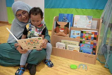 SUKA MEMBACA: Cik Junaida berkata beliau kini boleh menarik perhatian anaknya, Muhammad Jufry Shafiq Saharom, dua tahun, dengan cara penceritaan yang berlainan seperti menyanyi dan menari. - Foto BM oleh NG SOR LUAN