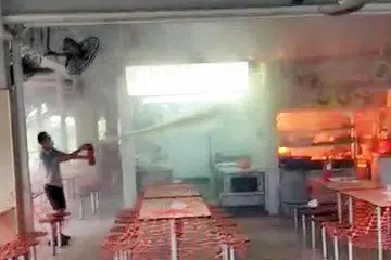 USAHA MEMADAMKAN KEBAKARAN: Seorang lelaki dilihat memadamkan api kebakaran di gerai di Pusat Penjaja Changi Village dengan menggunakan alat pemadam api. Menurut jurucakap SCDF, sebanyak 10 alat pemadam telah digunakan untuk memadamkan api itu sebelum ketibaan SCDF. - Foto PEMBACA