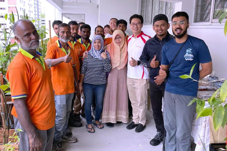 HULUR BANTUAN: Cik Maswati Masduki (empat dari kanan) bersama pekerja pembersihan kawasan Nee Soon, sukarelawan dan Encik Derrick Goh (berbaju putih) semasa sesi makan tengah hari sambutan Hari Raya di Blok 394, Yishun Clove.