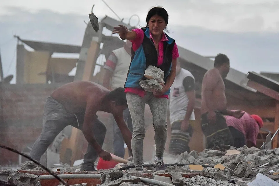 CARI ORANG TERSAYANG: Cik Veronica Paladines, dibantu beberapa orang, sedang mengangkat batu-bata dalam usaha mencari suaminya yang terperangkap di kawasan Tarqui, Manta. 