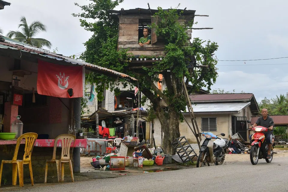 Encik Mohd Nor Afiq Mohd Anuar, 33 tahun, meninjau keadaan sekitar rumah dari pondok yang dibina atas pokok sebagai persiapan menghadapi musim tengkujuh di Kampung Kubang Tebakang, Pasir Mas, Kelantan.