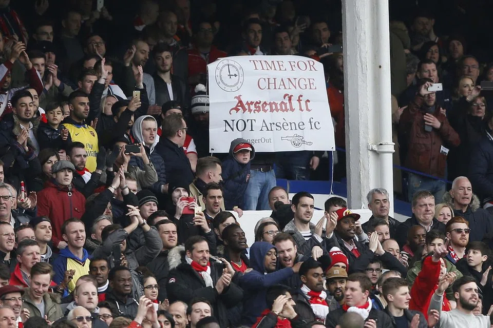 TUNJUK MARAH: Segelintir penyokong Arsenal melahirkan rasa tidak puas hati dengan prestasi pasukan mereka musim ini dengan mempamerkan poster yang tertera kekata meminta pengurus Arsene Wenger mengundurkan diri. - Foto REUTERS