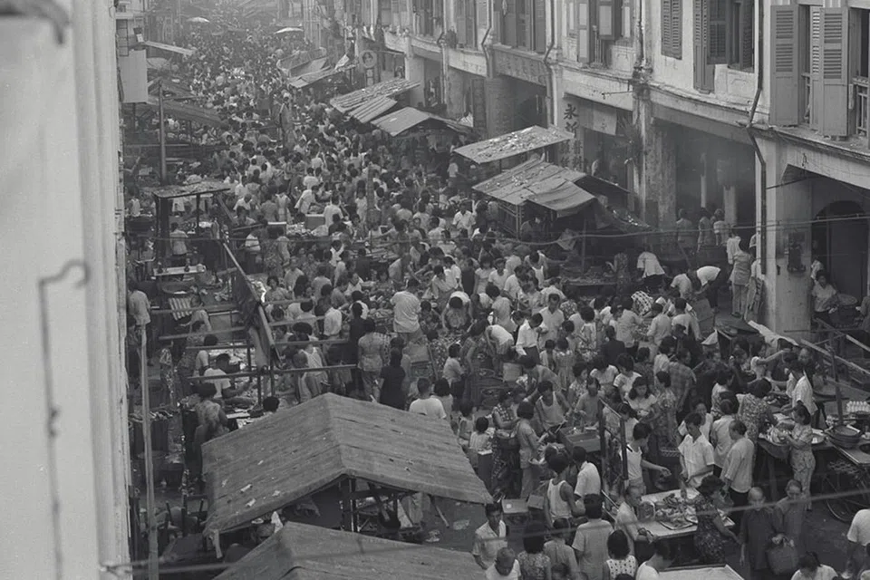 MENJEJAS WARGA TIDAK BERSALAH: Orang ramai membanjiri jalan raya untuk ke pasar dan kedai runcit apabila perintah berkurung berakhir buat sementara pada 5.30 pagi, 23 Julai 1964. - Foto fail 