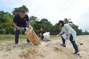 BERSIHKAN PANTAI: Encik Mohd Fahmi Aliman (kiri) bersama relawan Sharifah Sheikha Haroon Aljunied dan anaknya, Encik Daniyal Rashad Mohammad Yusri, mengutip sampah di pantai East Coast semasa kegiatan membersihkan pantai anjuran CDC South East pada Sabtu (17 Sep). - Foto BM oleh ALPHONSUS CHERN