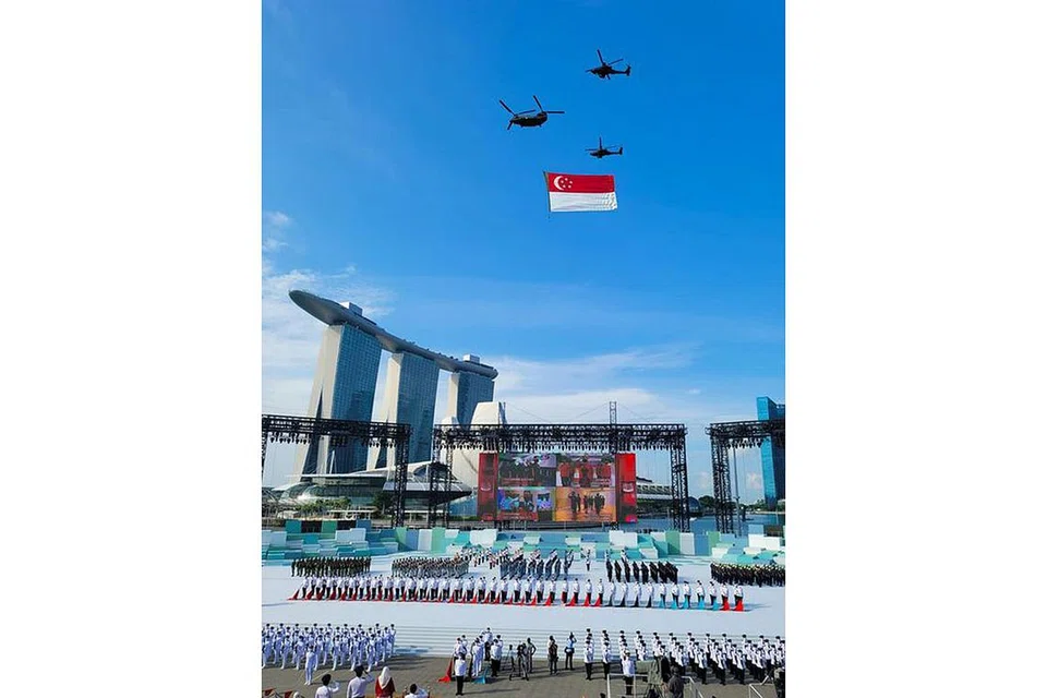 BERTEGUH BERSATU: Kontinjen perbarisan di platform Terapung Marina Bay ketika bendera Singapura dikibarkan dan Lagu Kebangsaan dimainkan. - Foto NG ENG HEN/FACEBOOK