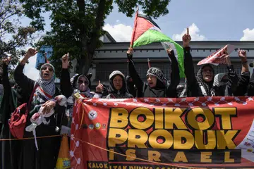 Penunjuk perasaan Pro-Palestin memegang sepanduk yang menyeru agar memboikot produk yang menyokong Israel semasa perhimpunan yang diadakan pada malam menjelang ulang tahun pertama konflik Israel-Hamas, di Bandung, Jawa Barat, pada 6 Oktober.