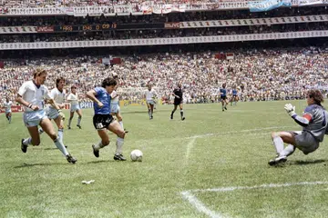 SAAT KECEMERLANGAN: Maradona (jersi biru) menggelecek melepasi pemain bek Terry Butcher (kiri) dan memperdaya penjaga gawang Peter Shilton (kanan) sebelum menjaringkan gol kedua Argentina, jaringan yang dianggap sebagai ''gol terbaik dalam abad'', ketika membantu negaranya mengalahkan England di suku akhir Piala Dunia Mexico 1986. - Foto AFP
