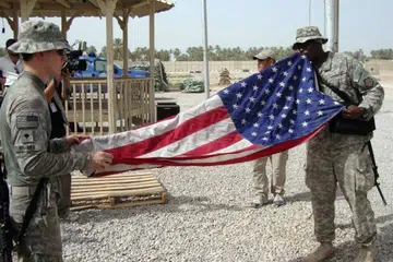 Anggota tentera Amerika Syarikat (melipat bendera negara itu di sebuah pangkalan tentera di Iraq. Tentera Amerika berundur dari pangkalan terakhir mereka di Iraq pada 30 September 2026, menamatkan satu lagi fasa kehadiran ketenteraan lebih dua dekad di negara itu, namun mencetuskan kebimbangan mengenai ancaman kebangkitan semula ISIS dan peningkatan pengaruh kumpulan bersenjata yang disokong Iran.