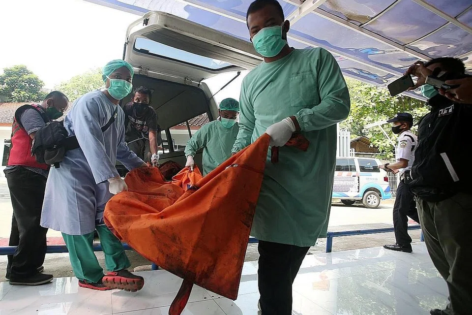 USAHA KENAL PASTI: Pekerja penjagaan kesihatan mengangkat beg mengandungi mayat seorang mangsa kebakaran penjara di Tangerang bagi pengenalan identiti di sebuah hospital. - Foto REUTERS