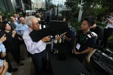 Dr Ng Eng Hen mencuba alat sekat dron yang dipamerkan Pasukan Polis Singapura sewaktu acara Memperingati Hari Pertahanan Mutlak 2024 di South Beach Tower pada 15 Februari.
