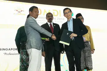 BANGUNKAN KEUPAYAAN HALAL: Pengarah Eksekutif SIM, Encik Ronald Tan (kanan) berjabat tangan dengan Encik Zuraimi selepas memeterai MOU dalam Konvensyen Dunia Melayu Dunia Islam (DMDI) ke-19 anjuran Jamiyah baru-baru ini. - Foto SIM