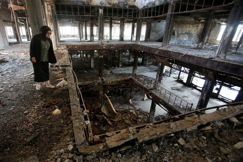 PERJUANGAN PELAJAR: Raghad Hammoudi di bangunan Perpustakaan Pusat Universiti Mosul yang musnah akibat pertempuran menentang militan ISIS. Beliau dan rakan-rakan pelajarnya sedang berjuang memulihkan perpustakaan itu. - Foto REUTERS