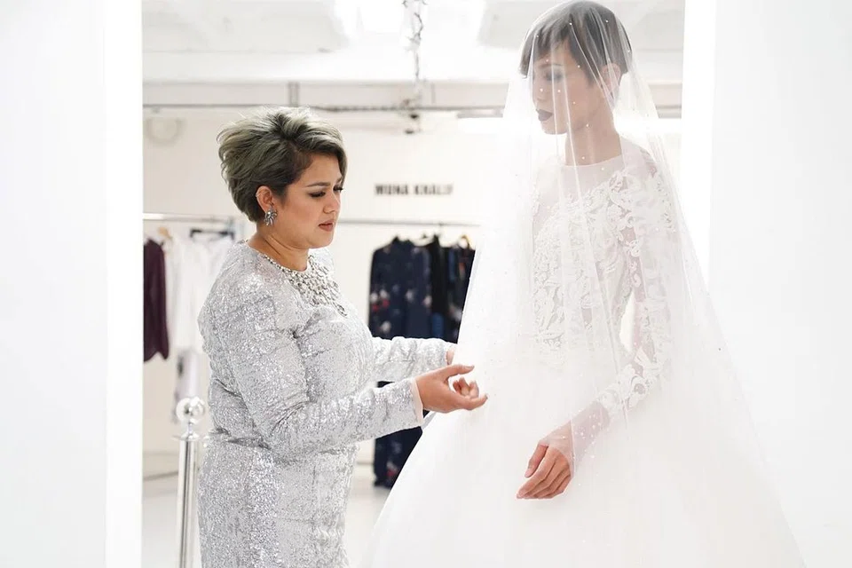 HIASAN LES: Fatimah Mohsin (kiri) memperkemas busana pengantin berwarna putih yang digayakan model terkenal Malaysia, Tinie. Busana yang siap dengan jahitan les bercorak unik ini membezakan Fatimah dengan pereka fesyen mapan lain.