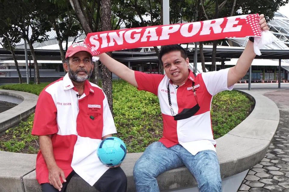 HARAP KEADAAN DIPERBAIKI: Faizal Jamil (kanan) bersama seorang lagi anggota, Akbar Hashim daripada kumpulan penyokong bola sepak Singapura, Singapore Die Hard Fans. 