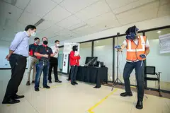 TINJAU LATIHAN: Encik Lawrence Wong (kiri) memerhatikan peralatan latihan simulasi VR yang ditunjukkan oleh dua penolong pengurus stesen SMRT, Encik Zul Fadli (kanan) dan Cik Amira Natasya (berbaju merah). - Foto ZAOBAO
