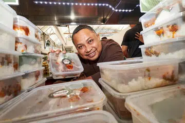 'NASI LEMAK POWER': Encik Badrol Hisam dengan bungkusan nasi lemak di gerainya yang terletak di Bazar Raya Utara. - Foto BH oleh ROSLEE ABDUL RAZAK