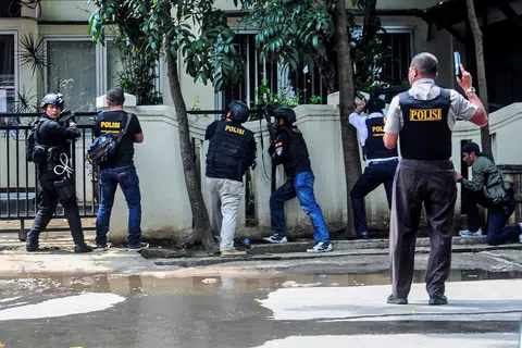 BERSIAP HADAPI PENYERANG: Pegawai polis dilihat dekat pejabat pemerintah tempatan menyusuli kejadian letupan di Bandung, Jawa Barat, Indonesia, semalam. Polis Indonesia menembak mati lelaki yang disyaki meletupkan bom itu. - Foto REUTERS