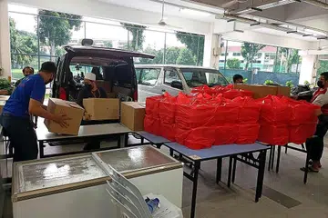 AGIH DAGING KORBAN: Sukarelawan di Masjid Al-Khair menyediakan paket makanan yang akan diagihkan kepada pekerja migran yang tinggal di dormitori. - Foto MUIS
