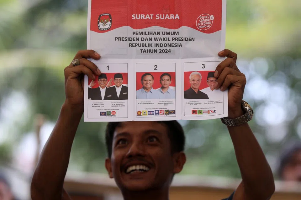 Seorang pegawai pilihan raya memegang undi semasa pengiraan undi di pusat mengundi di Banda Aceh, Indonesia.