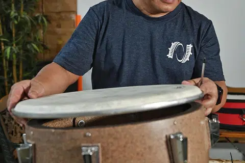 REBANA RINGAN: Encik Yaziz Hassan memasang rebana plastik yang dibuat menggunakan baki balang plastik yang dikitar semula.