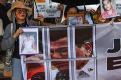 Keluarga mangsa pembunuhan di luar proses undang-undang dalam perang dadah bekas presiden Filipina Rodrigo Duterte (gambar pada sepanduk) mempamerkan potret orang tersayang mereka ketika protes di Manila pada 23 Februari 2026. Satu pendengaran bermula di Mahkamah Jenayah Antarabangsa (ICC) pada hari yang sama bagi menentukan sama ada Duterte akan dibicarakan berhubung sekurang-kurangnya 76 kematian tersebut. 